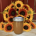 Zanne's Farm Pear Butter half pint jar with multicolored sunflowers spread out on rustic wood with red fence background