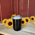 Zanne's Farm Blueberry Jelly half pint jar with sunflowers scattered loosely on rustic wood with red fence background